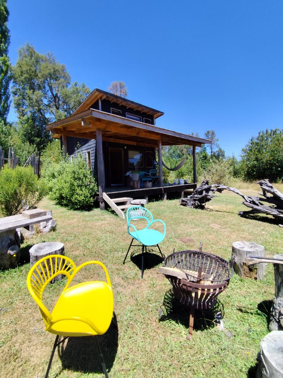 Un chalet rustique doté d’un porche couvert, de meubles d’extérieur et d’un foyer.