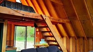 Ein gemütliches Loft-Zimmer mit Holzbalkendecke, einer Couch und einer Pendelleuchte.