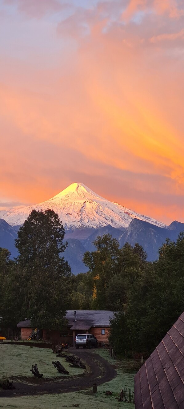 A mountain with a snow-capped peak, a wooden cabin, and a clear sky. - Ruka Kizel (Pucon)
