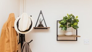 A wall with a hat hanging on a hook, a triangular wall decoration, and a potted plant on a shelf. - Stunning House in Heart of Historic Lincoln (Lincolnshire)