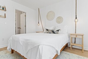 Une chambre à coucher avec un grand lit, une table de chevet et un luminaire suspendu.