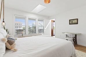 A bedroom with a large bed, a skylight, a desk with a chair, and a painting on the wall. - ACCESS TO EVERYTHING! <br>Enjoy comfort, convenience, and elegance during your stay at one of the most sought-after locations on Holden Beach! (Holden Beach)
