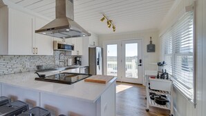 Una cocina moderna con armarios blancos, una isla grande y vistas al exterior.