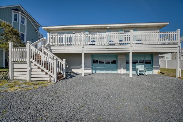 A two-story house with a front porch, a staircase, and a garage. - Beautiful Canal front home. Just a short walk to the beach! (Holden Beach)