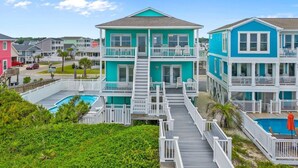 A multi-story residential building with a pool, a deck, and a staircase leading to the upper floors. - The Perfect Oceanfront Vacation w/ Private Pool! (Holden Beach)