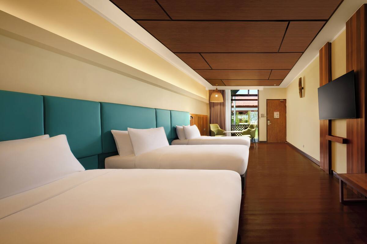 Una habitación de hotel con dos camas, un televisor y techo de madera.