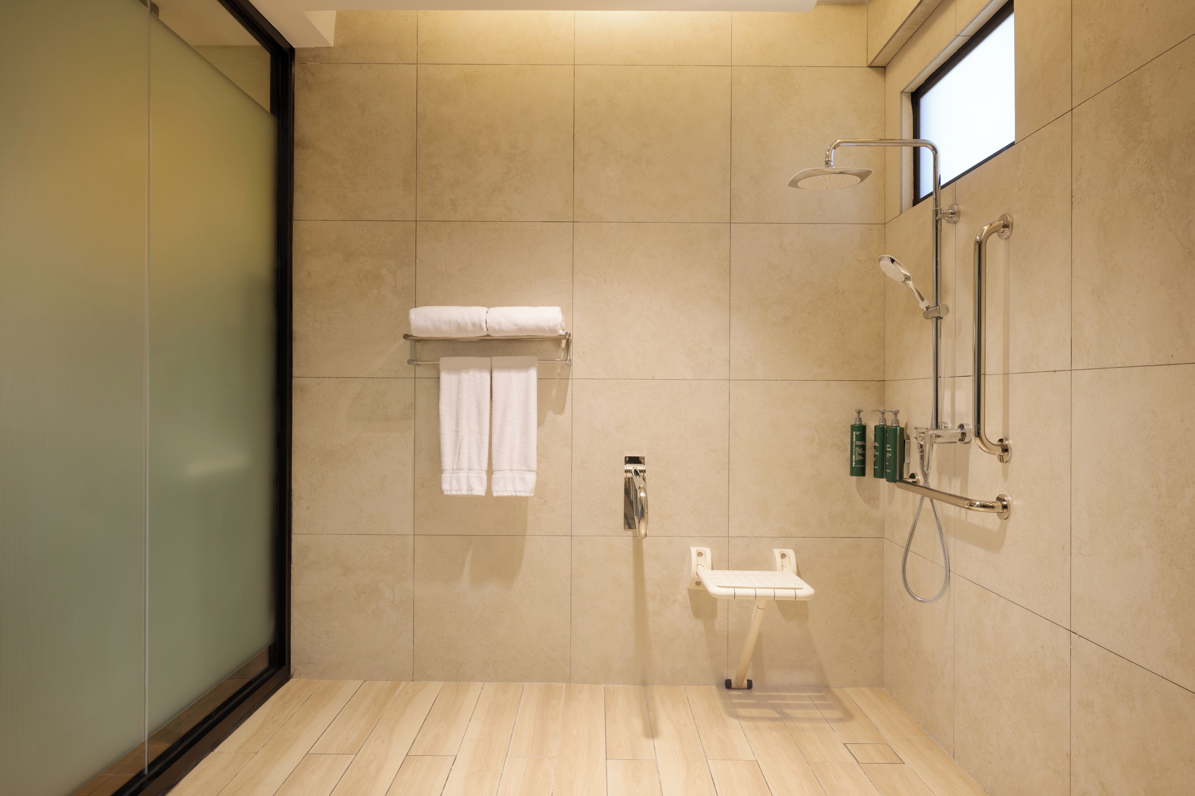 A modern bathroom with a glass shower enclosure, a white sink, and a towel rack.