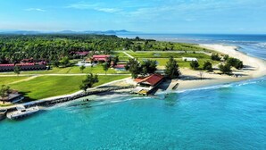 An aerial view of a coastal resort with a beach, clear waters, and lush greenery. - Hilton Garden Inn Kota Kinabalu Tuaran (Tuaran)