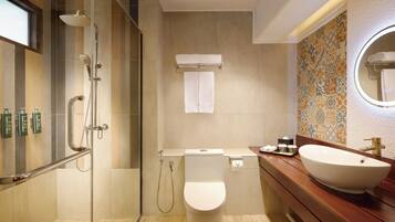 A modern bathroom with a glass-enclosed shower, a toilet, a sink with a large basin, and a mirror.