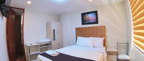 A hotel room with a bed, a wardrobe, a desk, and a chair.