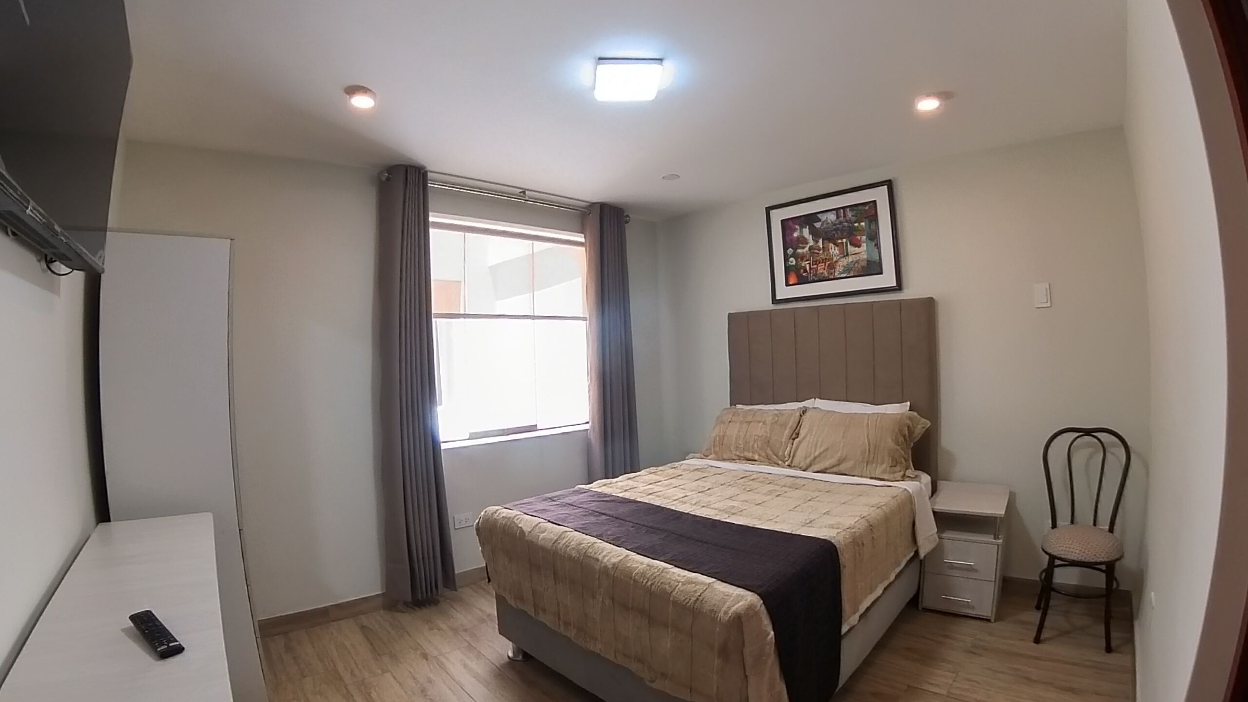 A bedroom with a bed, a chair, a desk, and a window with curtains.