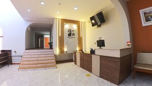 A hotel reception area with a marble floor, a reception desk, a staircase, and a wall-mounted TV. - Hotel Rosa Mistica Inn (Arequipa)