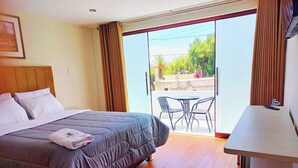 A hotel room with a bed, a desk, and a view of the outside. - Hotel Rosa Mistica Inn (Arequipa)