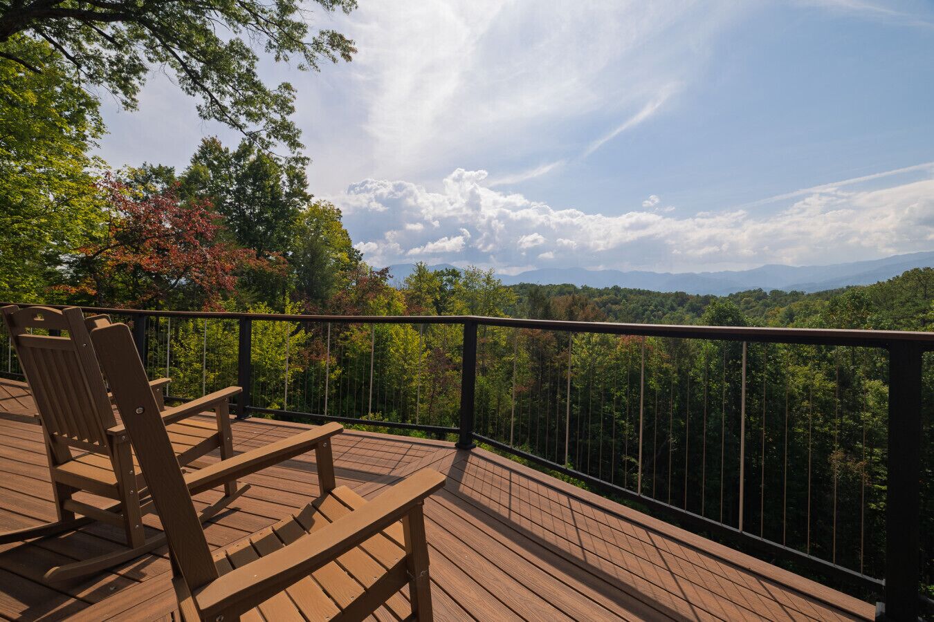 A wooden deck with a railing overlooking a forested landscape.