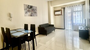 A modern living room with a dining area, a grey sofa, and a black dining table with chairs.