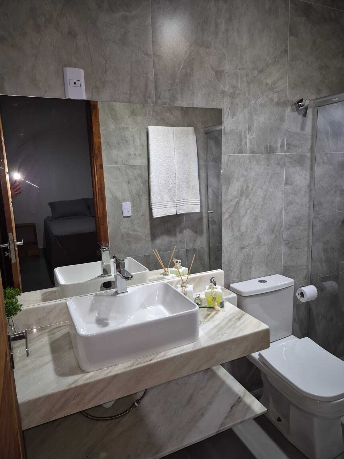 Een moderne badkamer met een grote spiegel, twee wasbakken, een toilet en een douche.