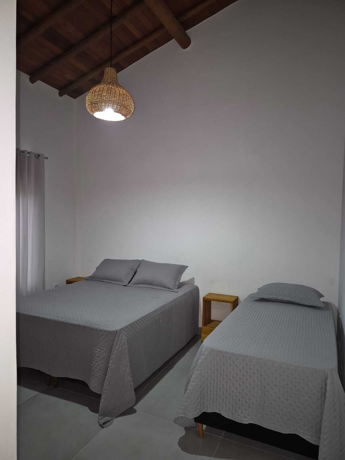 Ein Schlafzimmer mit zwei Betten, einer Pendelleuchte und einer Holzbalkendecke.
