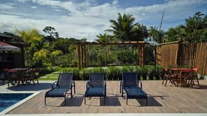 A pool area with three lounge chairs and a wooden deck. - Beach house in Arraial d`juda Bahia, close to the best beaches in the region. (Arraial d'Ajuda)