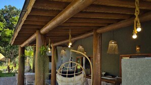 Un espace extérieur abrité, doté de poutres en bois, de luminaires suspendus et d’un fauteuil suspendu.
