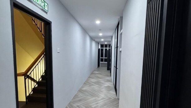 Un couloir avec un escalier, une porte portant l’inscription « Salon », et un sol à motifs.