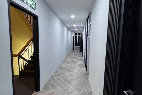 A hallway with a staircase, a door labeled 'Lounge,' and a patterned floor.