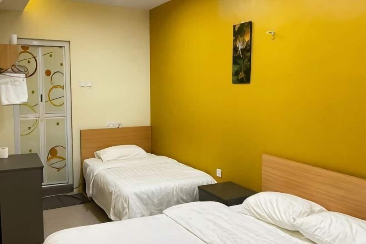 A hotel room with two beds, a wooden headboard, a small desk, a wardrobe, and a painting on the wall.