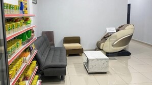 Une pièce comprenant un canapé, un fauteuil de massage, une petite table et des étagères remplies de produits.
