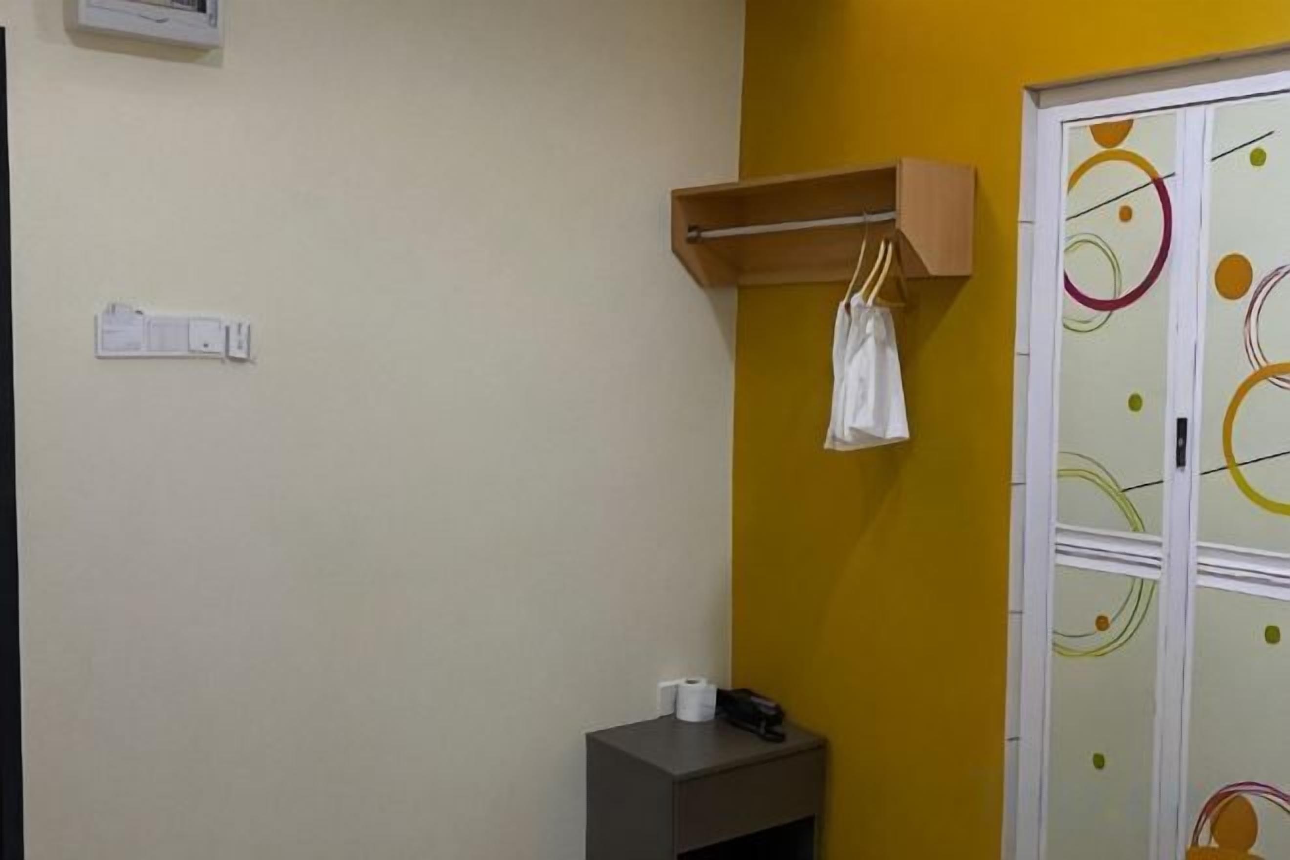 A bathroom with a towel hanging on a rack, a small table with a phone and a cup, and a door with a colorful pattern.