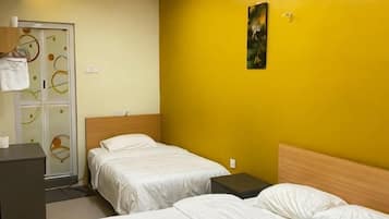 A hotel room with two beds, a wooden headboard, a small desk, and a door with a towel rack.