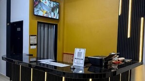 Un comptoir d’accueil doté d’un téléviseur à écran plat, d’une enseigne et d’un comptoir noir.