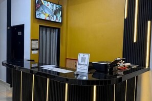 A reception desk with a flat-screen TV, a sign, and a black counter.