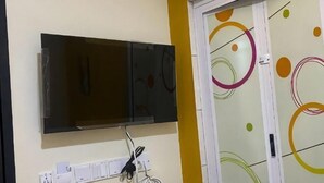 Un téléviseur fixé au mur, une prise de courant et une porte ornée de motifs circulaires colorés.