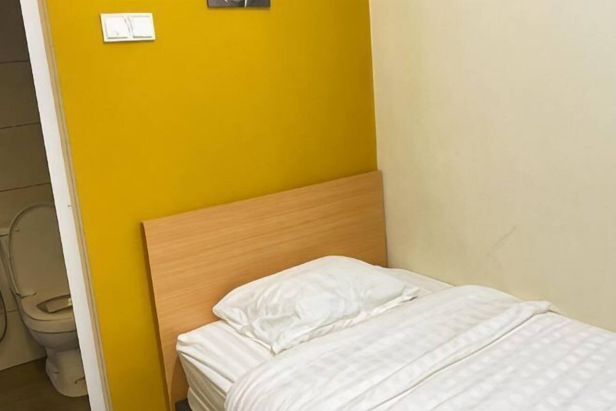 A single bed with a wooden headboard in a room with yellow and beige walls.