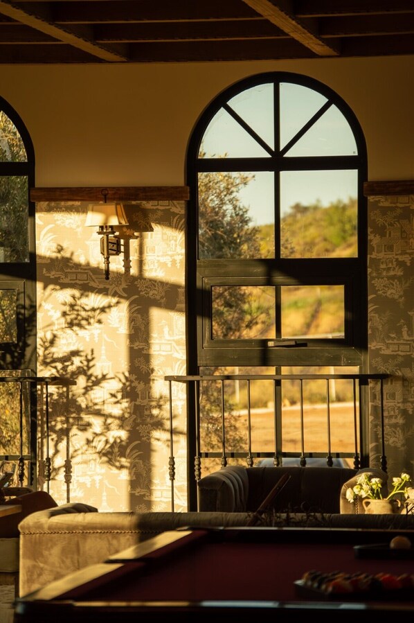 A room with a large arched window, a sofa, and a small table with a vase of flowers.
