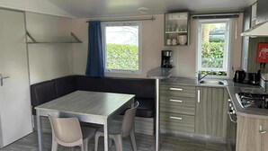 A compact kitchen with a dining area, a built-in stove, and a window with a view of greenery.