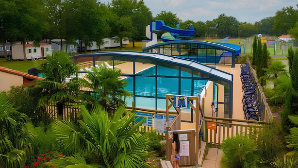 A swimming pool with a covered deck, surrounded by lush greenery and a row of blue chairs.
