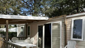 A wooden deck with a covered seating area, a sliding glass door, and a view of a neighboring house.