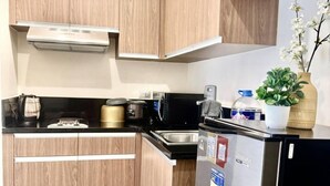 A compact kitchen with wooden cabinets, a stainless steel refrigerator, and a microwave.