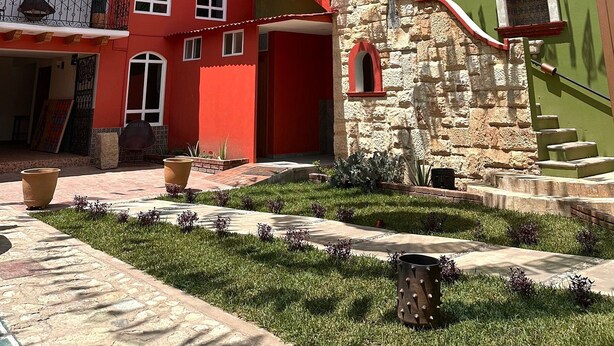 Un cortile con un edificio rosso, un muro in pietra e un muro verde con un murale.