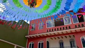 Un edificio con facciata rossa, numerose finestre e un balcone con ringhiere in ferro battuto.