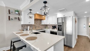 A modern kitchen with a large island, stainless steel appliances, and a herringbone-patterned backsplash. - Bluewater Resort 406 (Myrtle Beach)