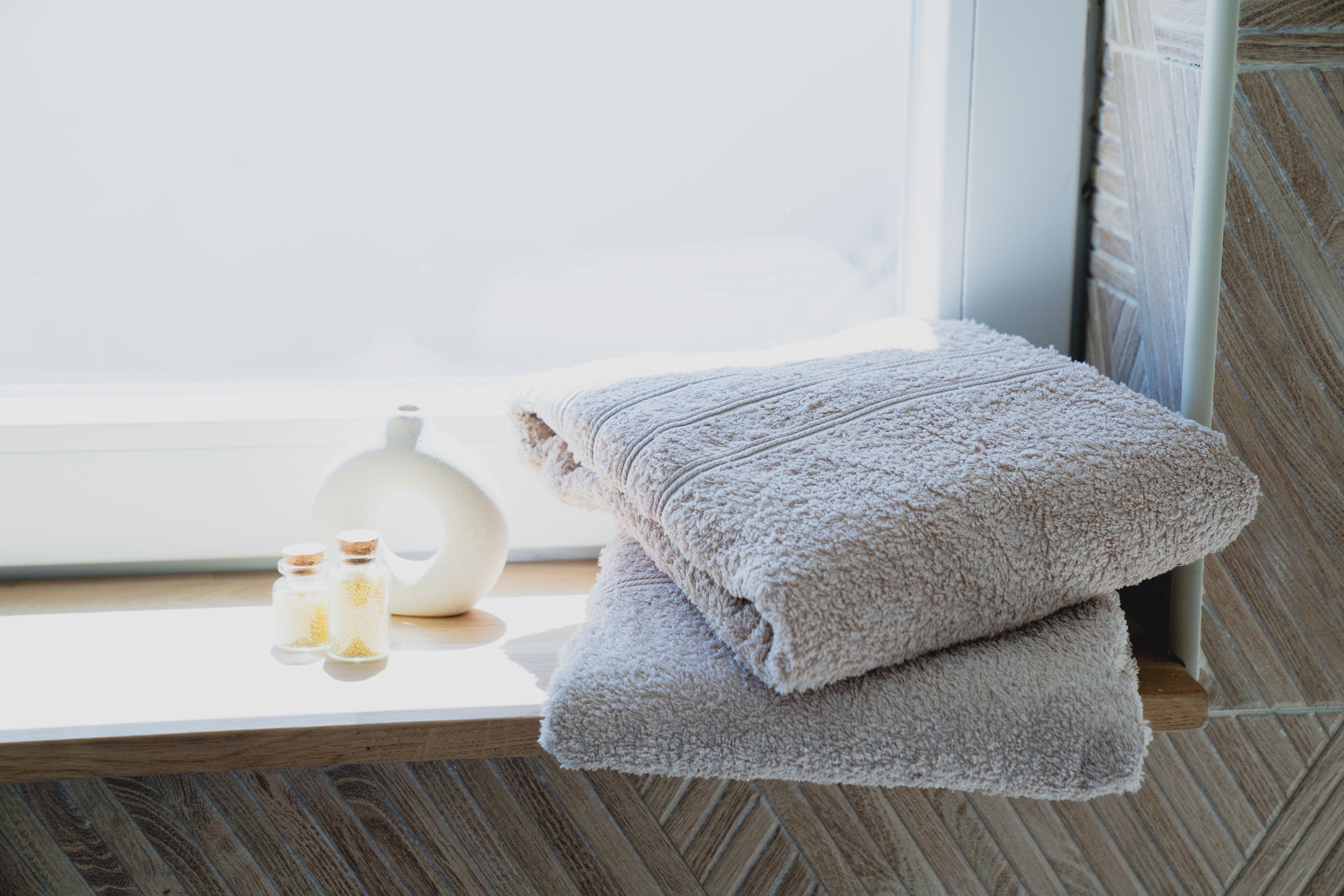 A bathroom with a wooden vanity, a white vase, and two bottles of lotion.