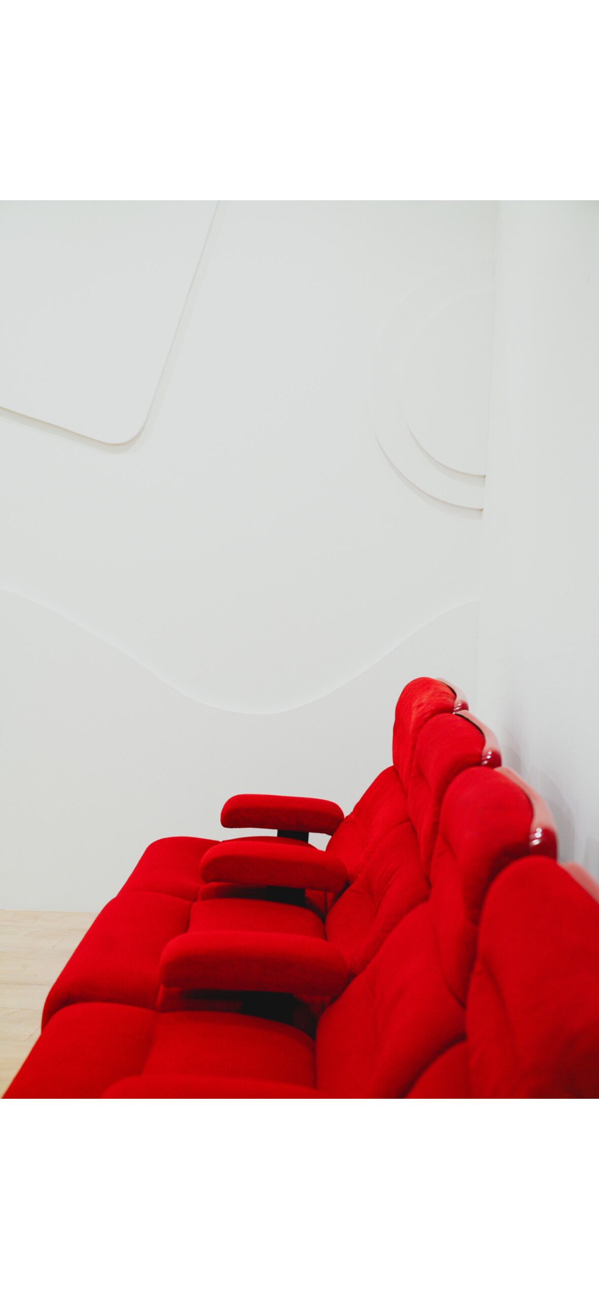 Ein rotes Sofa in einem Raum mit weißer Wand und Holzboden.