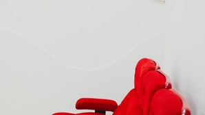 Un canapé rouge dans une pièce avec un mur blanc et un plancher en bois.