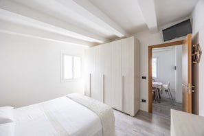 A bedroom with a bed, wardrobe, and a TV mounted on the wall.
