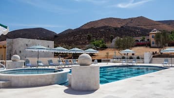 A pool area with multiple pools, lounge chairs, and umbrellas.