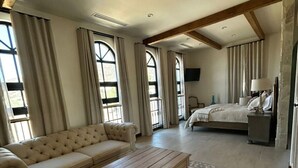 Ein geräumiges Zimmer mit einer großen Couch, einem Holztisch und einem Bett mit einem Nachttisch.