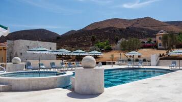A pool area with multiple pools, lounge chairs, and umbrellas.