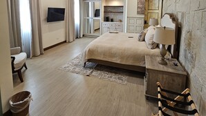 Ein Schlafzimmer mit einem Bett, einem Fernseher, einem Nachttisch aus Holz, einer Lampe und einer Steinwand.