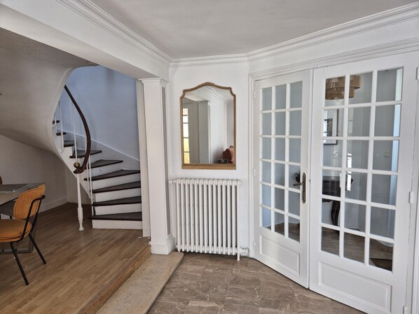 A staircase with a wooden handrail and a chair, a white radiator, and a door with glass panels.